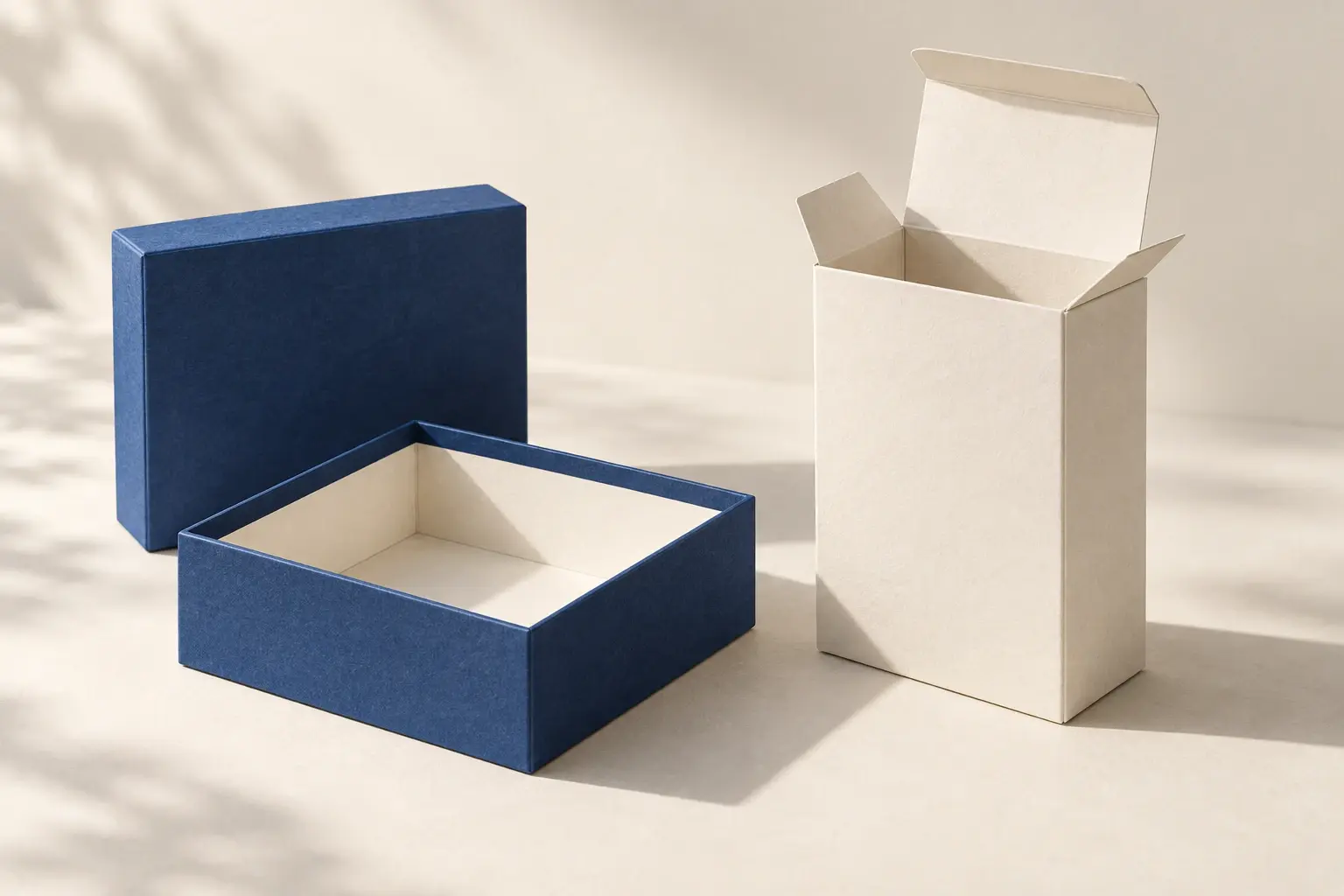 An open blue rigid box beside an ivory folding carton; original AI packaging concepts.
